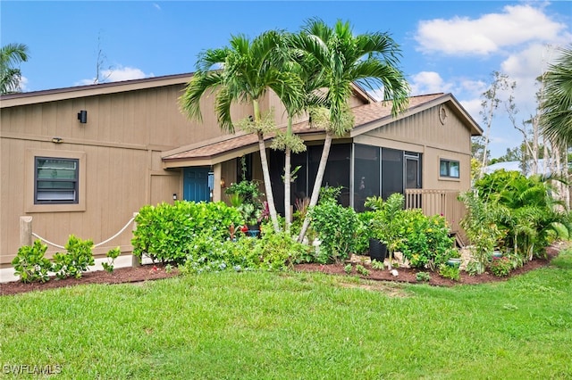 view of side of home featuring a sunroom and a yard