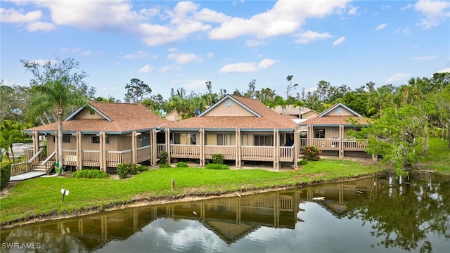 back of property with a water view and a lawn