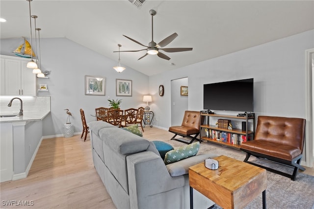 living room with lofted ceiling, ceiling fan, light wood-type flooring, and sink