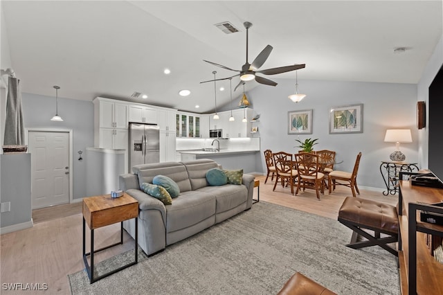 living room featuring light hardwood / wood-style floors, vaulted ceiling, ceiling fan, and sink