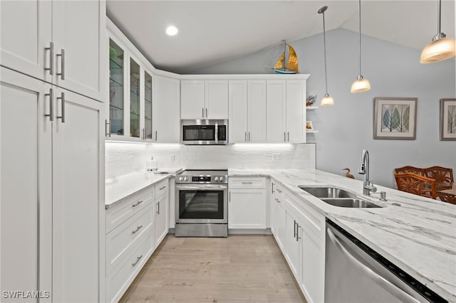 kitchen with stainless steel appliances, sink, pendant lighting, white cabinets, and lofted ceiling