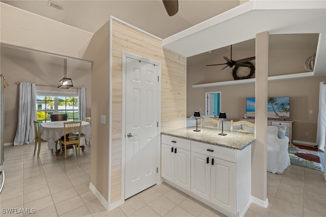 kitchen with light stone counters, white cabinets, light tile patterned floors, and ceiling fan