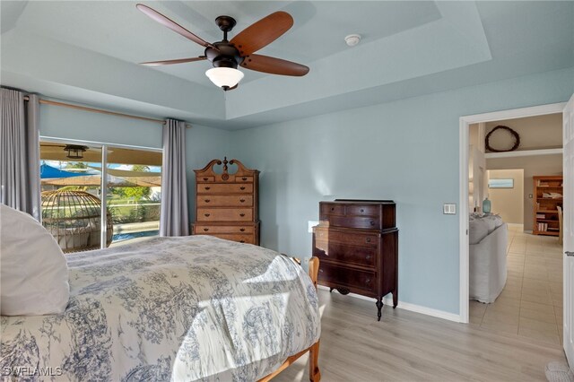 211 SW 21st Ln, Cape Coral, FL 33991 - bedroom with access to outside, a tray ceiling, baseboards, ceiling fan, and light wood-style floors