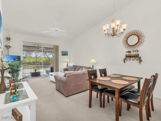 carpeted dining room with ceiling fan with notable chandelier and lofted ceiling