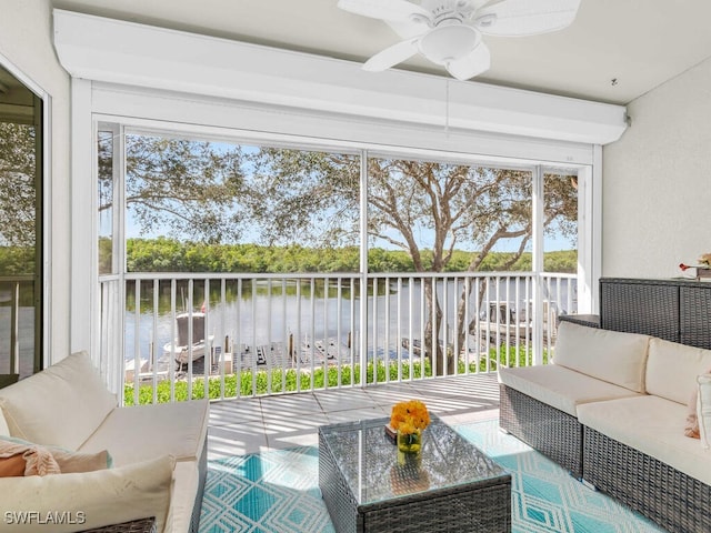 sunroom with ceiling fan and a water view