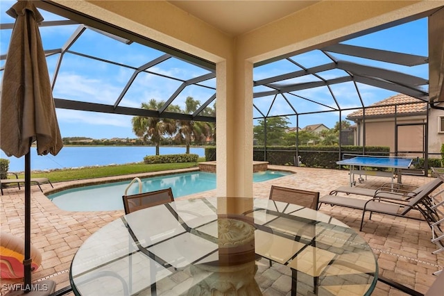 pool featuring glass enclosure, a patio, and a water view