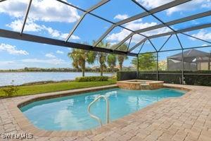 view of swimming pool with an in ground hot tub, a patio, a water view, and glass enclosure