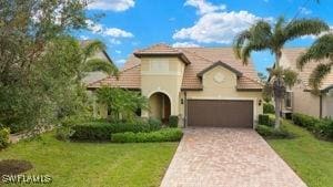 view of front of home featuring decorative driveway, a tile roof, stucco siding, an attached garage, and a front lawn