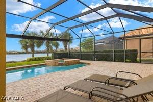 view of swimming pool with a lanai, a water view, a pool with connected hot tub, and a patio area