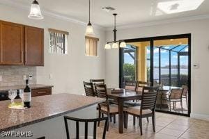 dining room with light tile patterned floors, ornamental molding, and baseboards