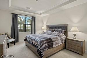 bedroom with a raised ceiling, light colored carpet, and crown molding