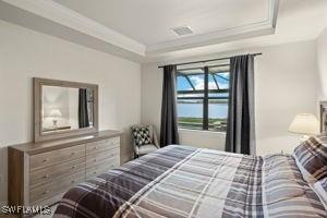 bedroom with visible vents, a tray ceiling, and crown molding