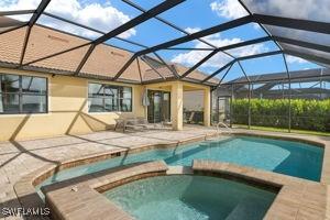 view of swimming pool featuring a lanai, a pool with connected hot tub, and a patio