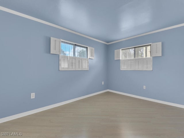 empty room featuring wood-type flooring and ornamental molding