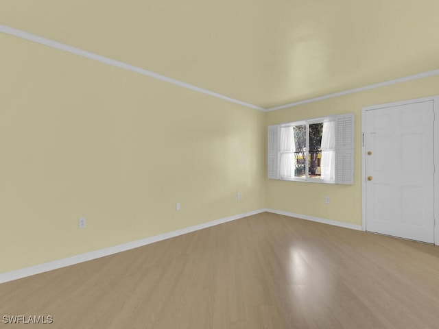 empty room featuring light wood-type flooring and crown molding