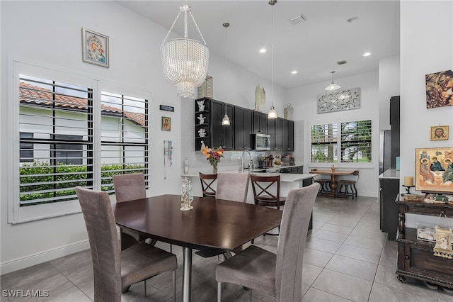 tiled dining room with a high ceiling, an inviting chandelier, and sink