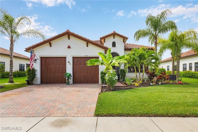 mediterranean / spanish-style home with a garage and a front lawn