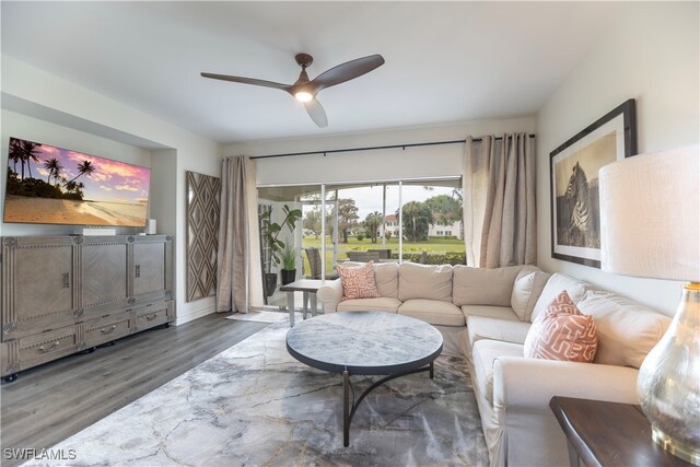 living room featuring ceiling fan and dark hardwood / wood-style floors