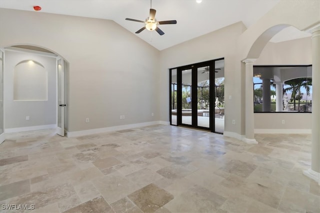 empty room featuring ornate columns, ceiling fan, french doors, and high vaulted ceiling