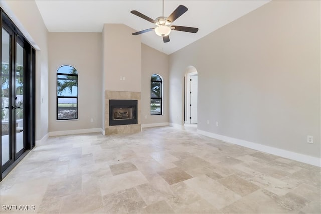 unfurnished living room with ceiling fan, high vaulted ceiling, and a tiled fireplace