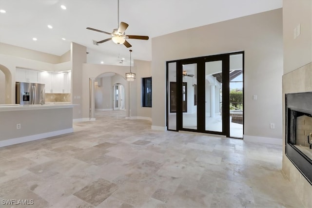 unfurnished living room with ceiling fan and a high ceiling