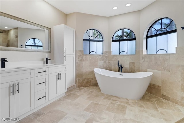 bathroom with a bathtub, tile walls, and vanity