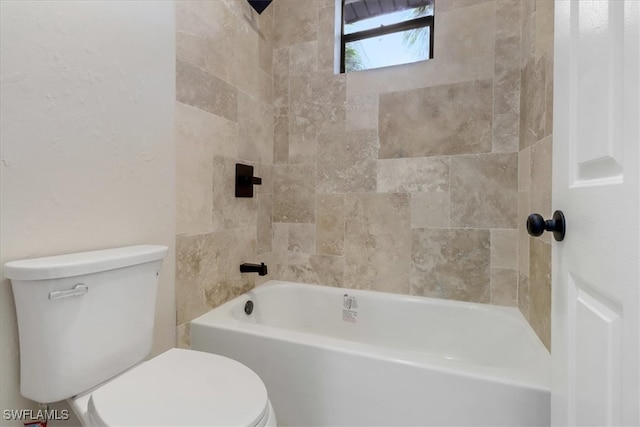 bathroom with tiled shower / bath combo and toilet