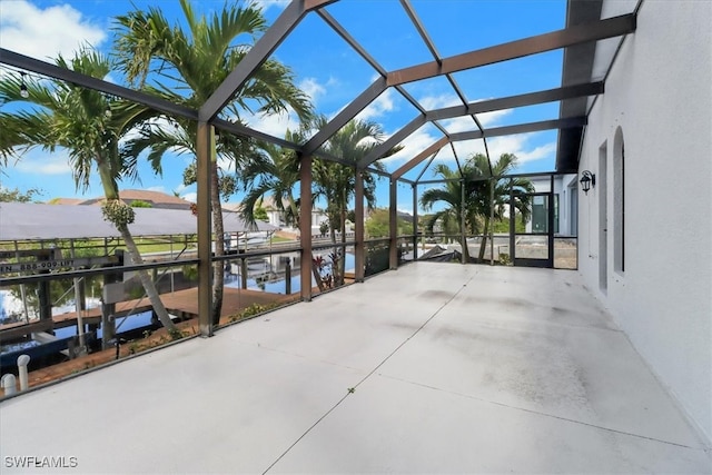 view of patio / terrace featuring a water view and glass enclosure