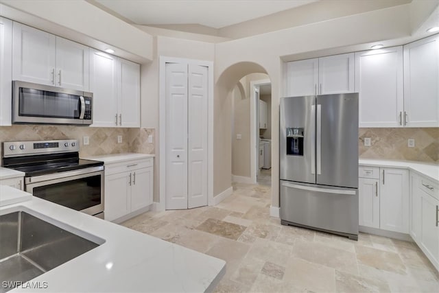 kitchen with decorative backsplash, white cabinetry, and appliances with stainless steel finishes