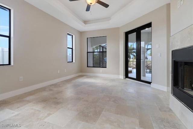 spare room with french doors, a tray ceiling, ceiling fan, and a healthy amount of sunlight