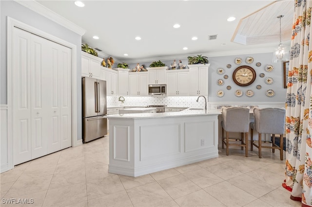 kitchen featuring white cabinetry, stainless steel appliances, light stone counters, and crown molding