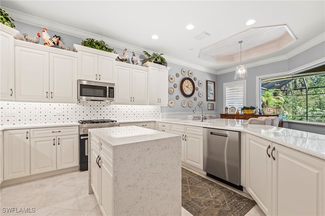 kitchen with stainless steel appliances, white cabinetry, ornamental molding, backsplash, and decorative light fixtures