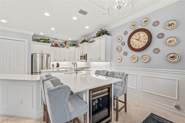 kitchen with white cabinetry, sink, wine cooler, appliances with stainless steel finishes, and a kitchen bar