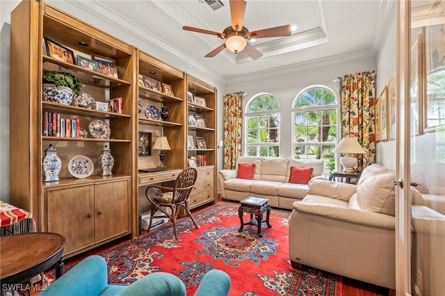 sitting room with a raised ceiling, ceiling fan, and crown molding