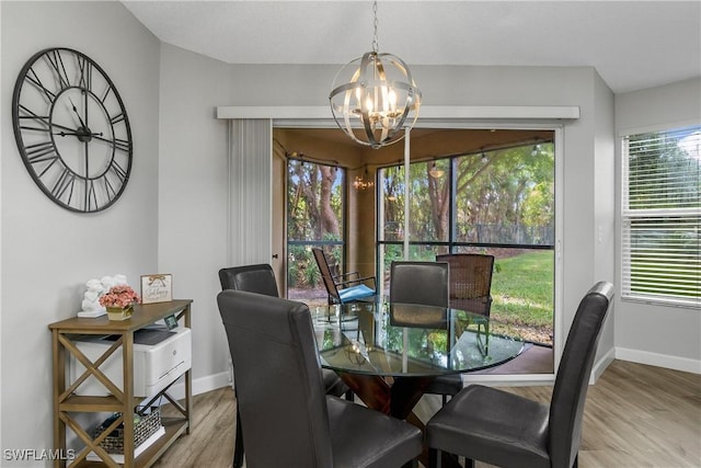 dining room featuring a healthy amount of sunlight, a notable chandelier, and light wood-type flooring