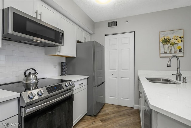 kitchen featuring wood-type flooring, appliances with stainless steel finishes, sink, and white cabinets