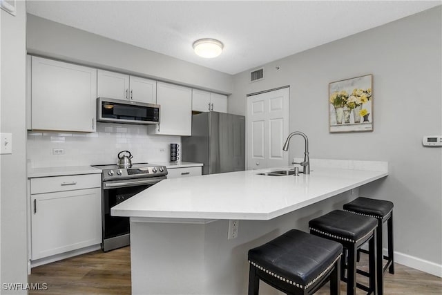 kitchen with sink, stainless steel appliances, a kitchen breakfast bar, and white cabinets