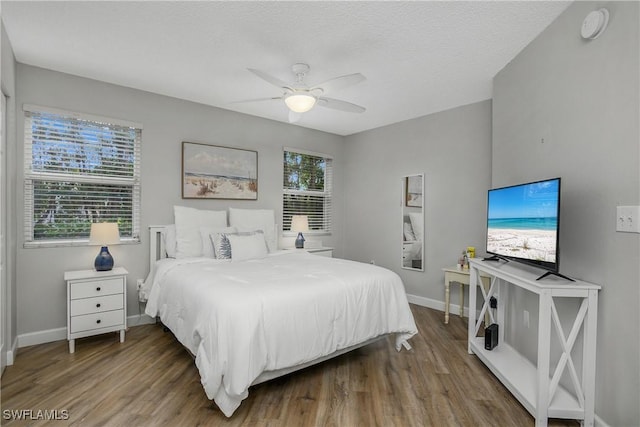 bedroom featuring ceiling fan, hardwood / wood-style floors, and a textured ceiling