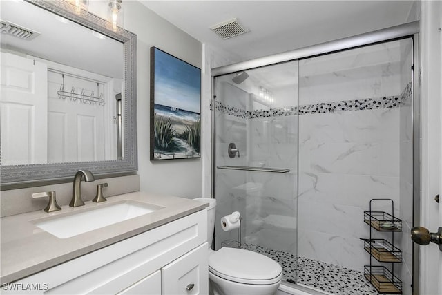 bathroom featuring vanity, a shower with shower door, and toilet