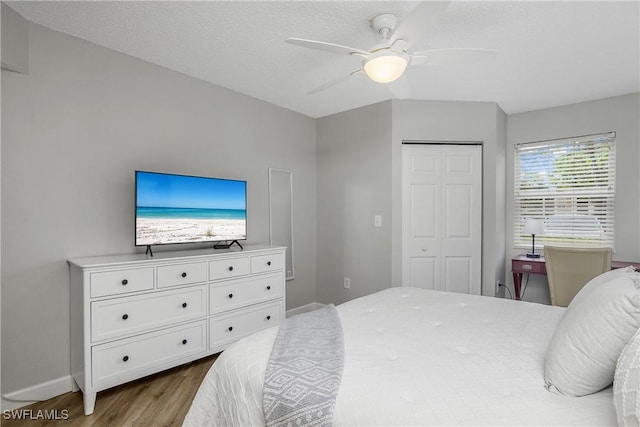 bedroom featuring hardwood / wood-style flooring, a textured ceiling, ceiling fan, and a closet