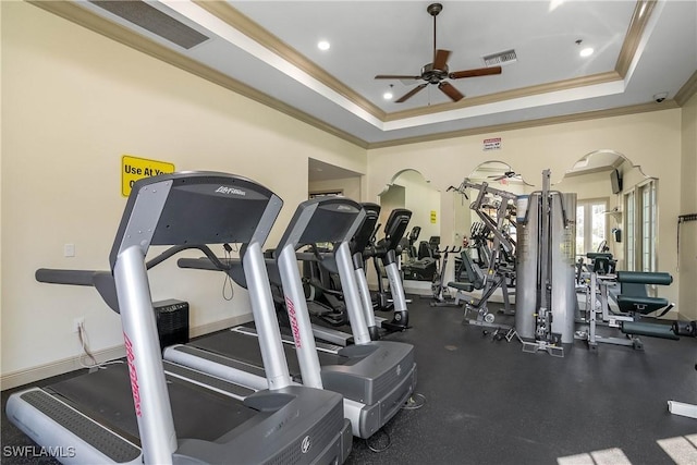 workout area featuring a raised ceiling, ornamental molding, and ceiling fan