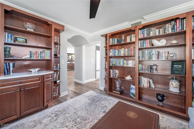 office space featuring baseboards, arched walkways, light wood-style flooring, ceiling fan, and crown molding