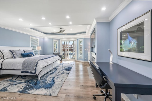 bedroom with light wood-style floors, a raised ceiling, crown molding, and recessed lighting