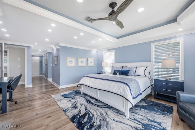 bedroom featuring a raised ceiling, multiple windows, wood finished floors, and visible vents