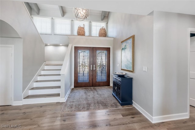 foyer with stairs, french doors, wood finished floors, and beam ceiling