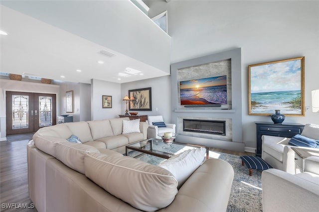 living area with french doors, recessed lighting, visible vents, a glass covered fireplace, and wood finished floors