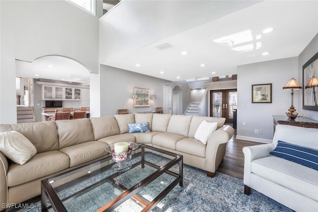 living area with visible vents, stairs, arched walkways, and dark wood finished floors