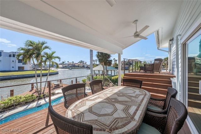 deck with outdoor dining space, a water view, a ceiling fan, and an outdoor pool