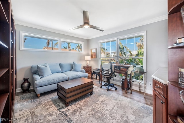 living area featuring ornamental molding, wood finished floors, baseboards, and a ceiling fan