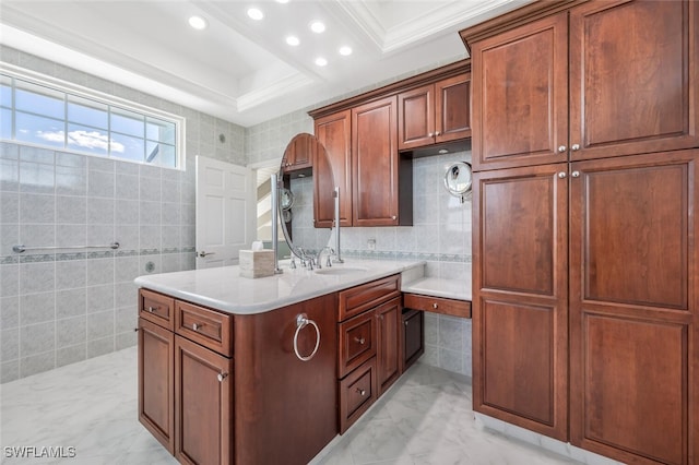 interior space with a kitchen island, ornamental molding, a sink, light countertops, and tile walls